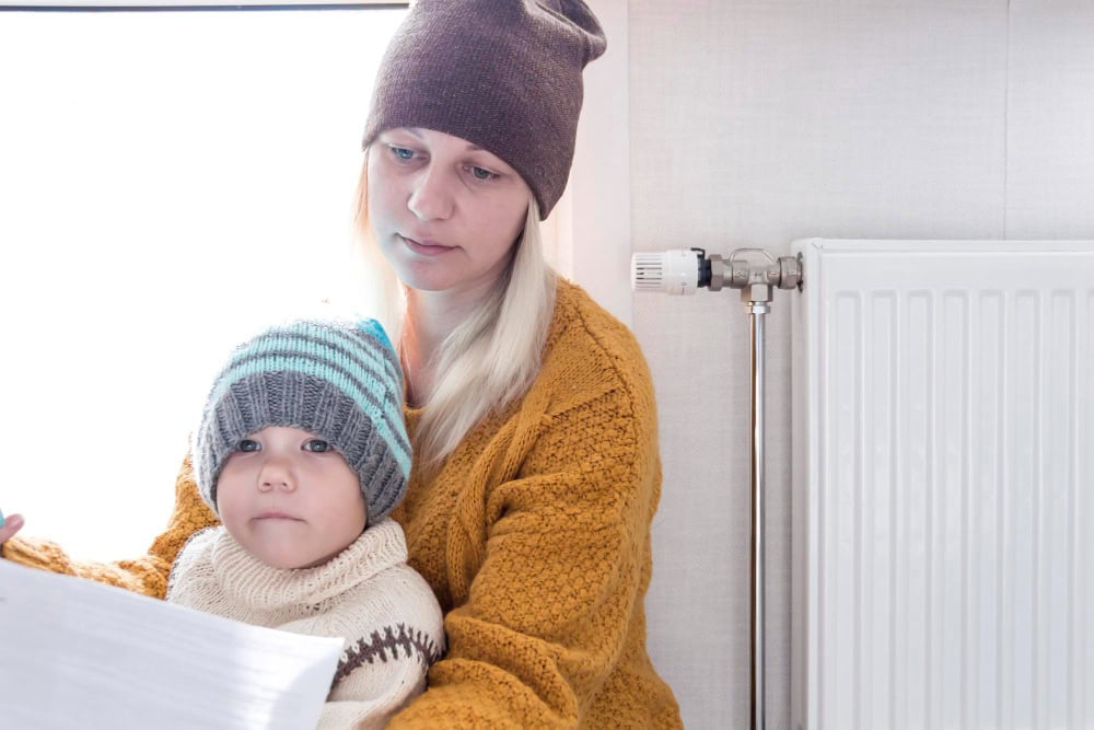 Woman and child in winter clothes by radiator.